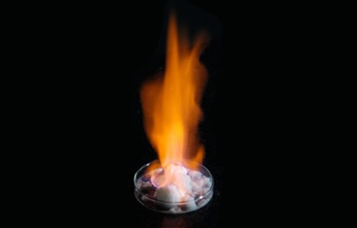 図１ 下の白い塊が人工のメタンハイドレート結晶。地表の温度・圧力では、この物質は水とメタンに分解し、そのメタンに火がついて燃えている。